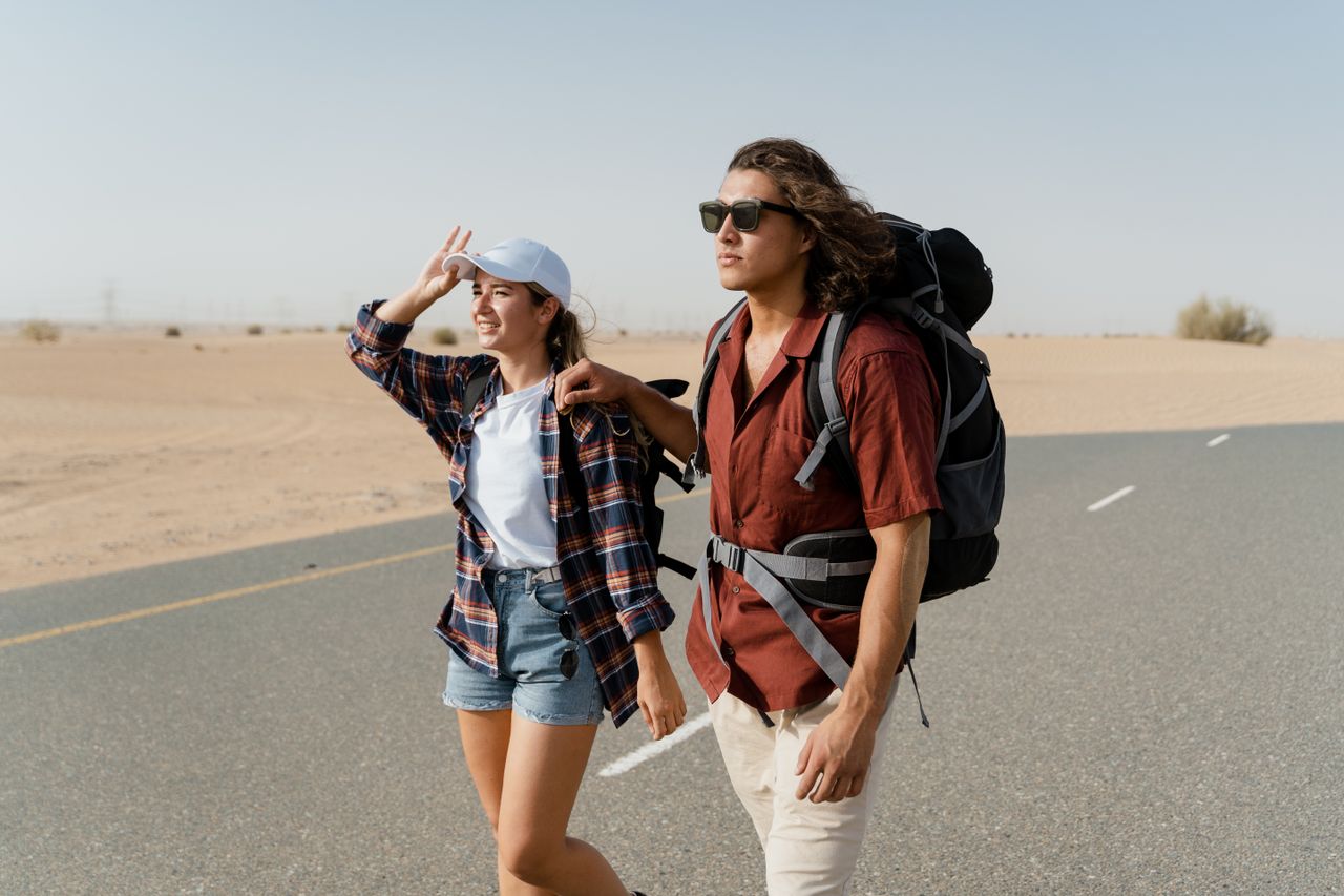 about-img-01 Young couple backpacking through a desert road, capturing wanderlust and exploration.